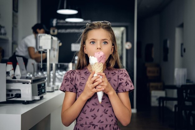 Jong mooi meisje in een jurk, ijs eten in een café.