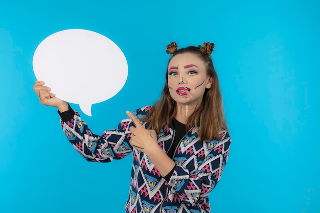 Jong mooi meisje met creatieve make-up en wijs met de vinger naar het ideebord. Hoge kwaliteit foto