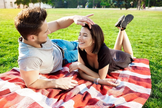 Jong mooi paar glimlachend rustend op picknick in park
