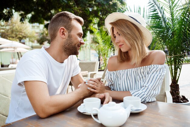 Jong mooi paar spreken, glimlachen, die in koffie rusten.