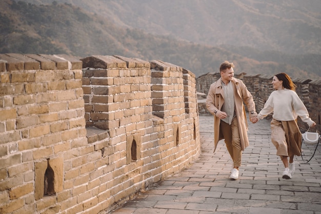 Gratis foto jong paar dat en bij de grote muur van china loopt tolt