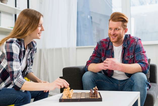 Jong paar die het schaakbord in de woonkamer thuis spelen