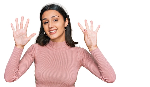 Jong spaans meisje dat vrijetijdskleding draagt en met vingers nummer negen naar boven wijst terwijl ze zelfverzekerd en gelukkig glimlacht