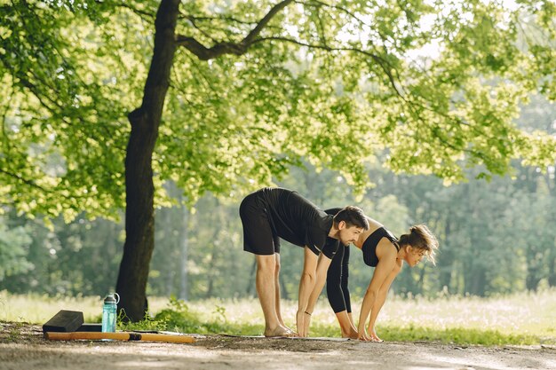 Jong sportief paar dat yogageschiktheid doet. Mensen in een zomerpark.