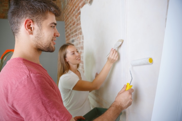 Jong stel doet appartement reparatie samen zelf. Getrouwde man en vrouw die huis make-over of renovatie doen. Concept van relaties, familie, liefde. Samen de muur schilderen en lachen.