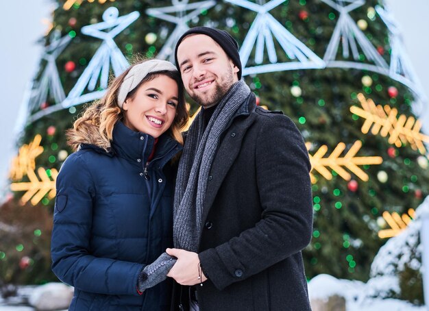 Jong stel in de buurt van een kerstboom in de stad, genietend van tijd samen doorbrengen