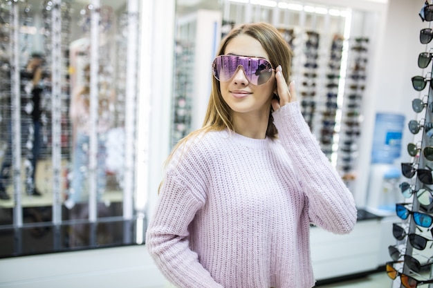 Jong studentmeisje bereidt zich voor op studie en probeert een nieuwe bril voor haar perfecte look in de winkel