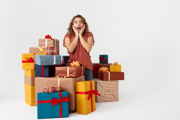 Jong verrast krullend vrouw onder geschenkdozen