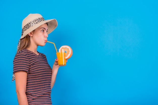 Jong vrouw het drinken jus d&#39;orange op blauwe achtergrond