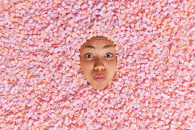 Jong vrouwelijk model met gevouwen lippen steekt hoofd in marshmallow