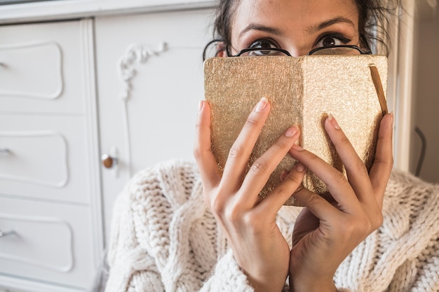 Jong vrouwen verbergend gezicht achter agenda