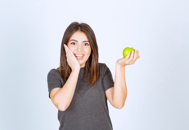 jong vrouwenmodel dat een groene appel houdt.