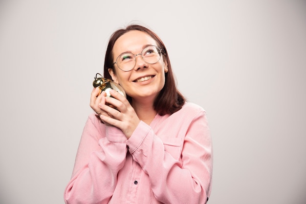 Jong vrouwenmodel dat een wekker op een witte achtergrond houdt. Hoge kwaliteit foto