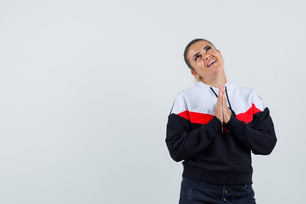 Jong wijfje dat iets in kleurrijk sweatshirt wenst en hoopvol, vooraanzicht kijkt.