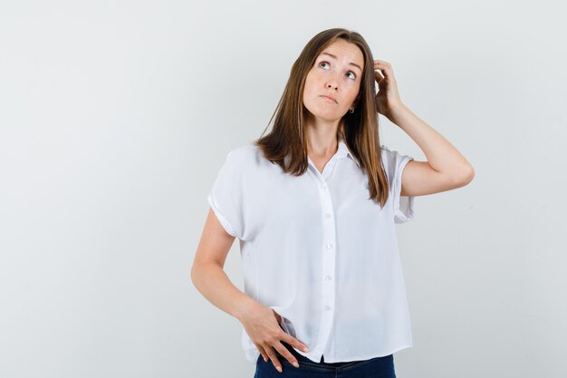 Jong wijfje dat in witte blouse weg kijkt en perplex kijkt