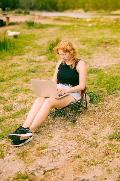 Jong wijfje dat laptop in bos met behulp van