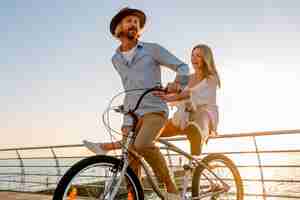 Gratis foto jonge aantrekkelijke man en vrouw reizen op de fiets, romantisch koppel op zomervakantie aan zee op zonsondergang, boho hipster stijl outfit, vrienden samen plezier