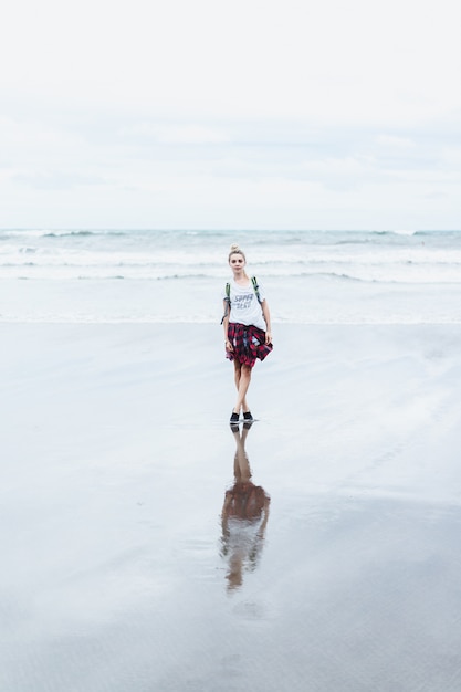 jonge aantrekkelijke vrouw die langs de oceaankust op een zandig strand loopt