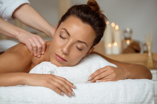 Jonge aantrekkelijke vrouw die massage het ontspannen in kuuroordsalon heeft.