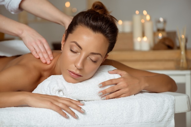 Jonge aantrekkelijke vrouw die massage het ontspannen in kuuroordsalon heeft.