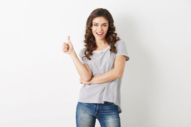 Jonge aantrekkelijke vrouw gekleed in casual outfit t-shirt en spijkerbroek met positief gebaar, glimlachen, gelukkig, hipster stijl, geïsoleerd, gekruld, duim omhoog