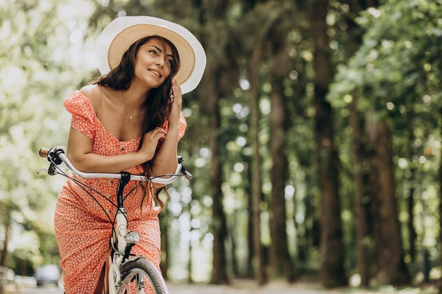 Jonge aantrekkelijke vrouw in kleding berijdende fiets en het gebruik van telefoon