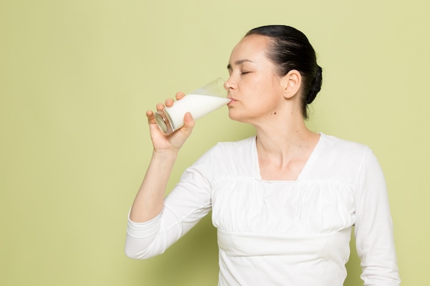 Jonge aantrekkelijke vrouw in wit overhemd drinkglas met melk