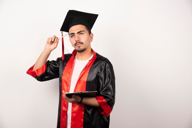 Jonge afgestudeerde student met diploma denken op wit.