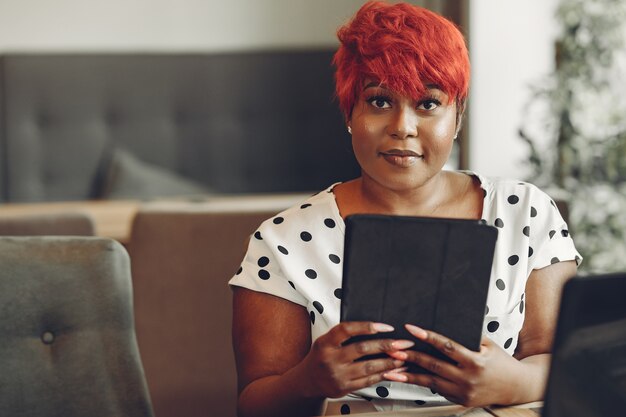 Jonge African American vrouw werkt in een kantoor. Dame in een witte blouse.