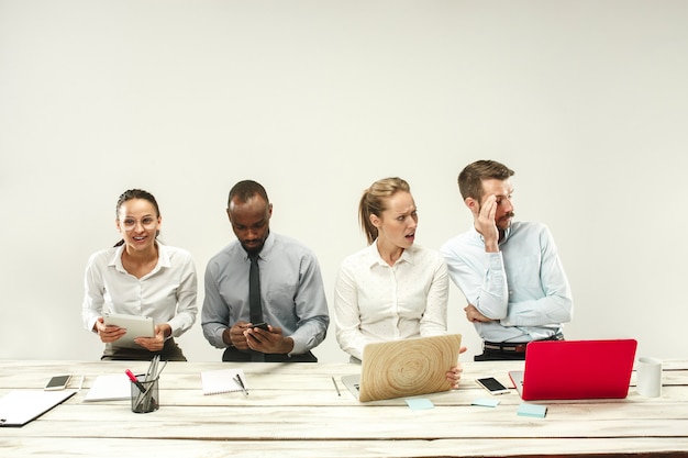 Gratis foto jonge afrikaanse en blanke mannen en vrouwen die op kantoor zitten en op laptops werken. het bedrijf, emoties, team, teamwerk, werkplek, leiderschap, vergaderconcept. verschillende emoties van collega's