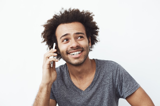 Gratis foto jonge afrikaanse man die lacht spreken op telefoon.