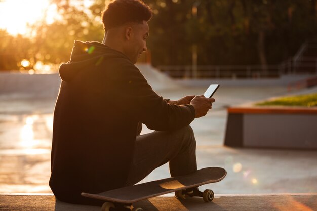 Jonge Afrikaanse man met behulp van mobiele telefoon