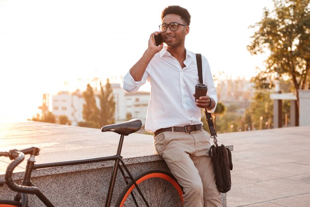 jonge Afrikaanse man ochtend met fiets praten via de telefoon.