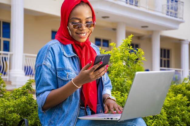 Jonge Afrikaanse vrouw aan het werk terwijl ze met haar laptop in een park zit