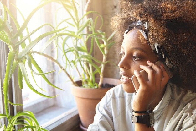 jonge Afrikaanse vrouw met krullend haar praten over de telefoon