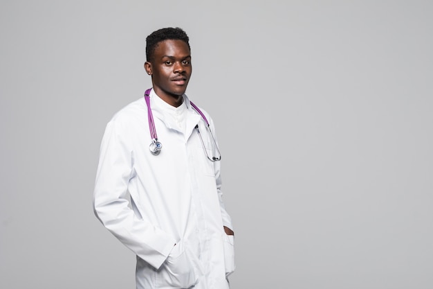 Jonge Afro-Amerikaanse arts in wit uniform geïsoleerd op een witte achtergrond staan met armen in pokdalig uitziende professioneel en zeer bekwaam op het gebied van medische specialisatie