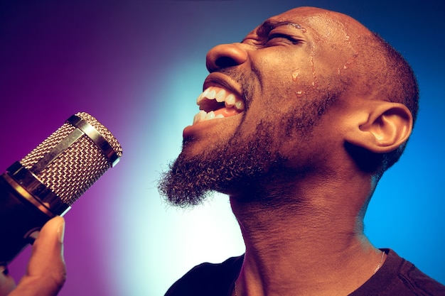 Jonge Afro-Amerikaanse jazzmuzikant zingt een lied op kleurovergang paars-blauw