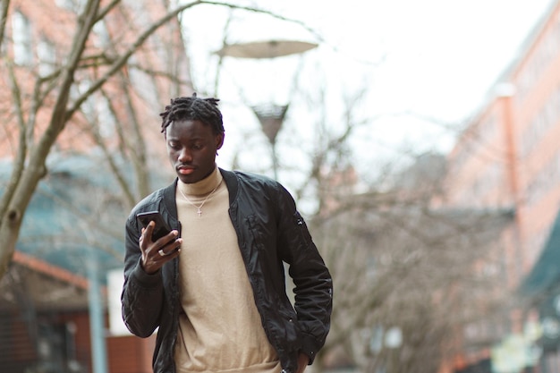 Gratis foto jonge afro-amerikaanse man die zijn telefoon gebruikt in de straten van lyon in frankrijk