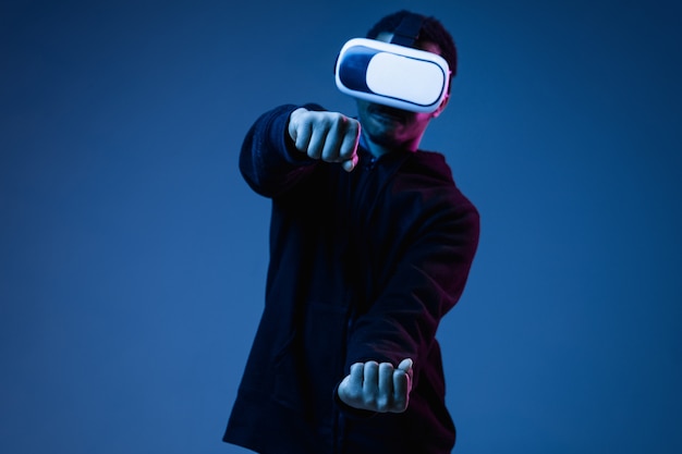 Jonge Afro-Amerikaanse man in VR-bril in neon op blauw