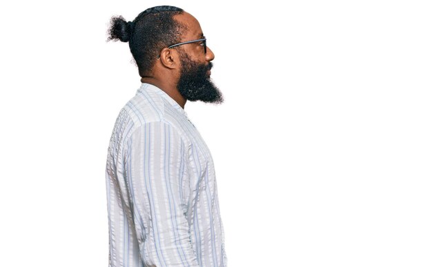 Jonge afro-amerikaanse man met een zakelijk overhemd en een bril die naar de zijkant kijkt, ontspannen profiel pose met een natuurlijk gezicht met een zelfverzekerde glimlach