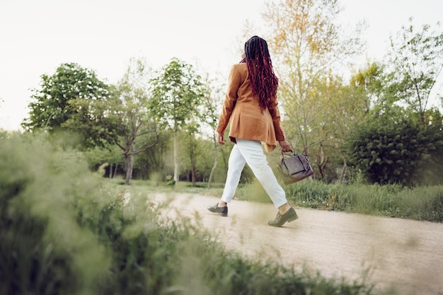 Gratis foto jonge afro-amerikaanse vrouw die een wandeling maakt in een park