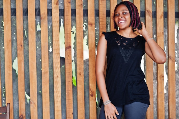 Jonge afro-amerikaanse vrouw poseerde tegen houten muur