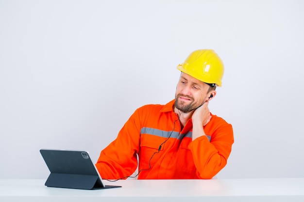 Jonge architect man met nekpijn kijkt naar zijn tabletcamera op witte achtergrond