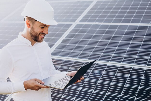 Jonge architect staat bij zonnepanelen en maakt diagnostiek op de computer