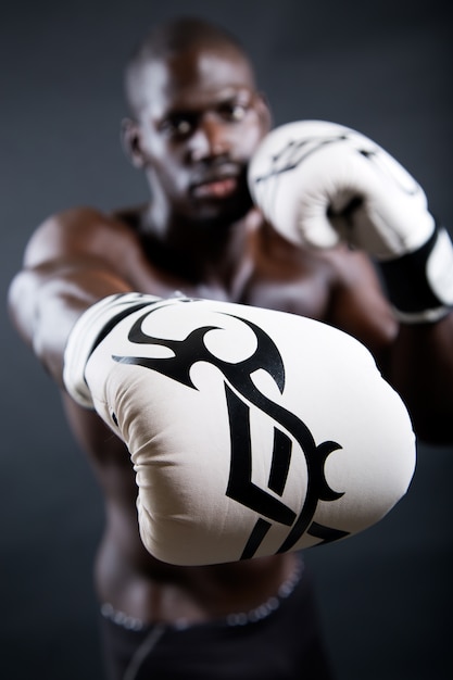 Jonge atletische bokser dragen handschoenen in zwarte achtergrond.