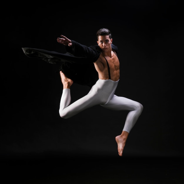 Jonge atletische man in stijlvolle kleding springen en dansen