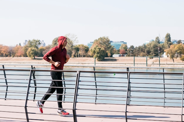 Jonge atletische man in sweatshirt hoodie lopen op park