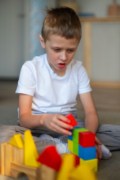 Gratis foto jonge autistische jongen die thuis met speelgoed speelt