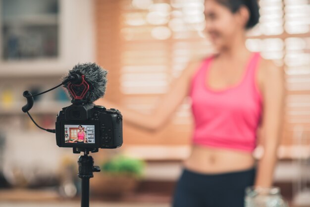 Jonge Aziatische blogger vrouw oefenen en kijken naar de camera in de keuken