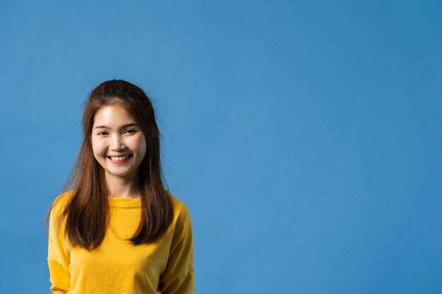 Jonge Aziatische dame met positieve uitdrukking, brede glimlach, gekleed in casual kleding en camera kijken op blauwe achtergrond. Gelukkige schattige blije vrouw verheugt zich over succes. Gezichtsuitdrukking concept.